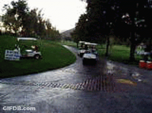 A Row Of Golf Carts Are Parked On The Side Of A Road . GIF