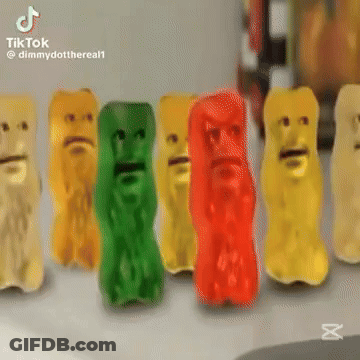 A Row Of Gummy Bears With Faces On Them Are Sitting On A Table . GIF