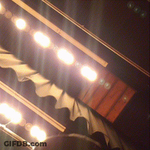 A Row Of Lights Are Shining On A Stage With A Curtain Behind Them GIF