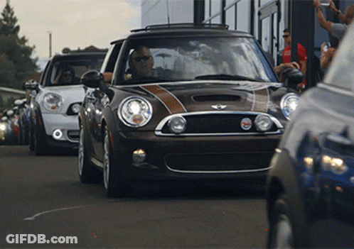 A Row Of Mini Cooper 'S Are Parked On A Street GIF