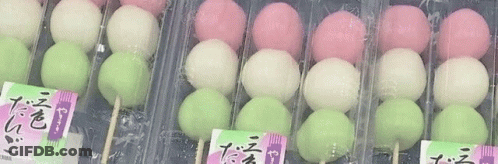 A Row Of Pink , White , And Green Balls On Sticks In Plastic Containers . GIF