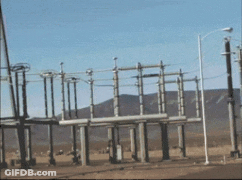A Row Of Power Lines Are Lined Up In A Field With Mountains In The Background GIF