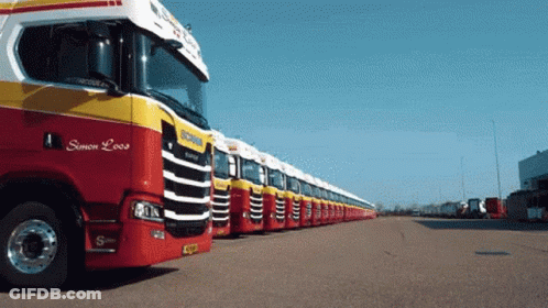 A Row Of Red And Yellow Scania Trucks Are Parked In A Lot GIF