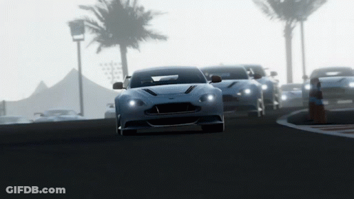 A Row Of Sports Cars Are Driving Down A Road With Palm Trees In The Background GIF