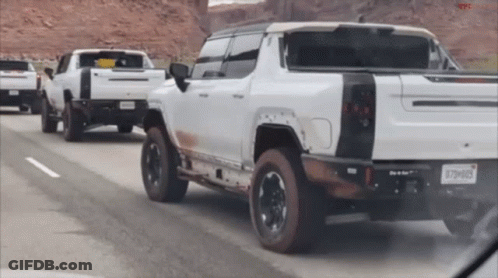 A Row Of White Trucks Are Driving Down A Highway And One Of Them Has A License Plate That Says X79h083 GIF
