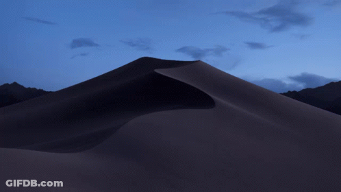 A Sand Dune With Mountains In The Background And A Purple Sky GIF