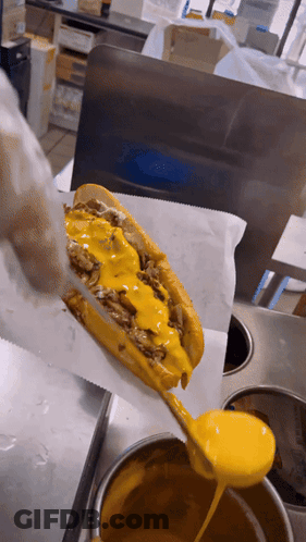 A Sandwich With Cheese And Meat Is Being Covered In Yellow Sauce GIF