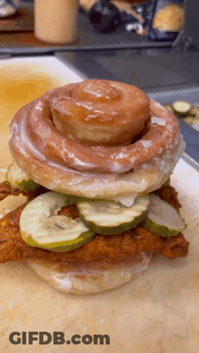 A Sandwich With Pickles And A Cinnamon Roll On Top GIF