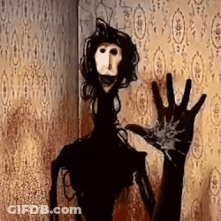 A Scary Doll Is Standing In Front Of A Wall With A Hand Reaching Out . GIF