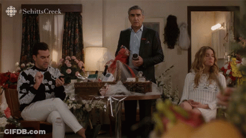 A Scene From Schitt 'S Creek Is Shown In A Room With Flowers GIF