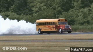 A School Bus Driving Down A Road With Smoke Coming Out Of It GIF