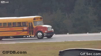 A School Bus Is Driving Down A Road With Flames Coming Out Of The Wheels GIF