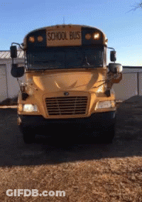A School Bus Is Parked In A Dirt Lot GIF