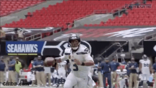 A Seahawks Football Player Is Running With A Ball GIF