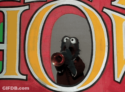 A Sesame Street Character Is Playing A Trumpet In Front Of A Sign That Says Hot GIF