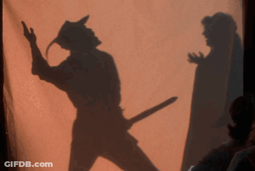 A Shadow Of A Man Holding A Sword Is Behind A Woman GIF
