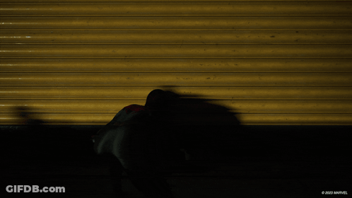 A Shadow Of A Spider Man Is Cast On A Yellow Wall With The Marvel Logo In The Corner GIF