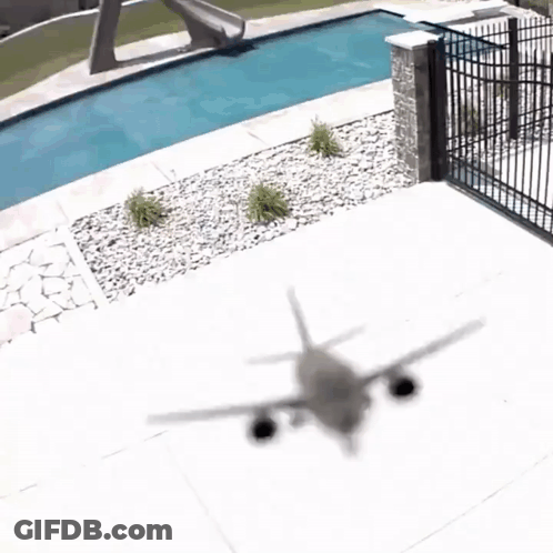 A Shadow Of An Airplane Is Cast On The Ground Near A Swimming Pool GIF