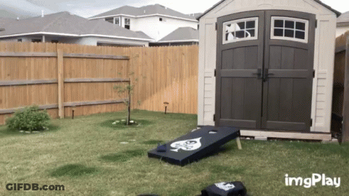 A Shed In A Backyard With A Bag Toss Game In Front Of It And The Words Imgplay On The Bottom GIF