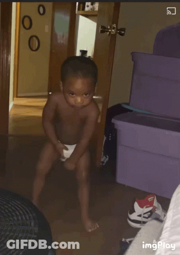 A Shirtless Baby Is Standing In A Room With A Purple Container In The Background GIF