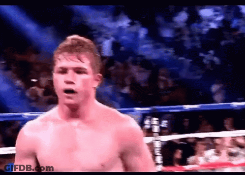 A Shirtless Boxer In A Boxing Ring With A Crowd In The Background GIF