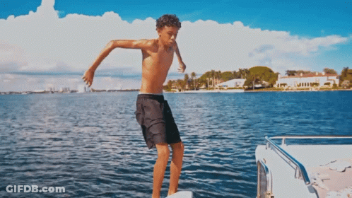A Shirtless Boy In Black Shorts Jumps Into The Water GIF