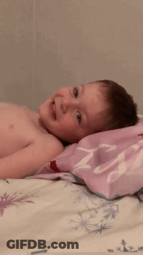 A Shirtless Child Is Laying On A Bed With A Pink Pillow That Says ' Princess ' On It GIF