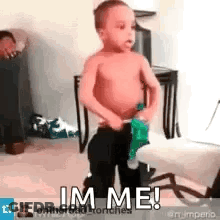 A Shirtless Little Boy Is Standing In A Room Holding A Bottle Of Soda And Says `` Im Me '' . GIF