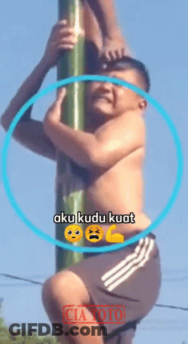 A Shirtless Man Climbs A Pole With The Words Aku Kudu Kuat On The Bottom GIF