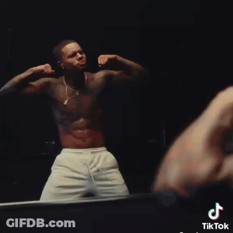 A Shirtless Man Flexes His Muscles In Front Of A Mirror With Tiktok Written On The Bottom Right GIF