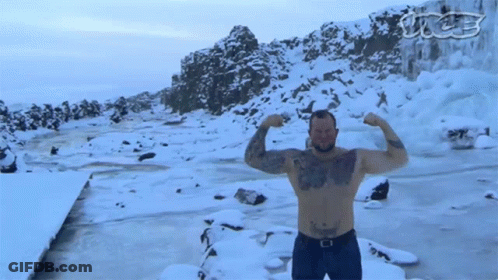 A Shirtless Man Flexes His Muscles In Front Of A Snowy Landscape GIF