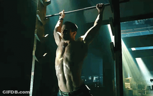 A Shirtless Man Hangs Upside Down On A Bar GIF