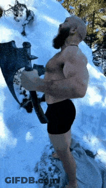 A Shirtless Man Holding A Large Axe In The Snow GIF