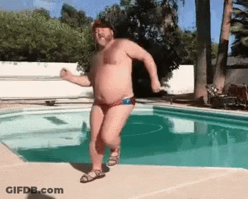 A Shirtless Man In A Bathing Suit Is Dancing In A Pool . GIF