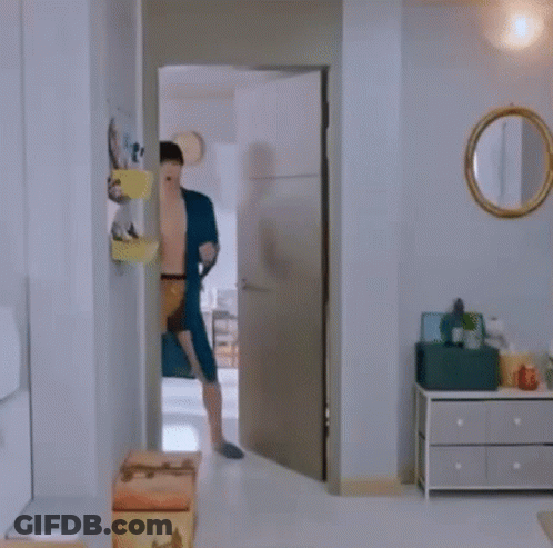 A Shirtless Man In A Blue Robe And Underwear Is Dancing In A Room . GIF