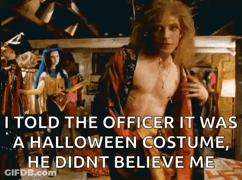 A Shirtless Man In A Halloween Costume Is Standing In Front Of A Woman In A Blue Dress . GIF