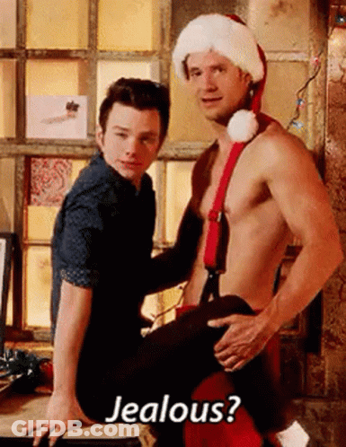 A Shirtless Man In A Santa Hat Is Sitting On A Man 'S Lap . GIF