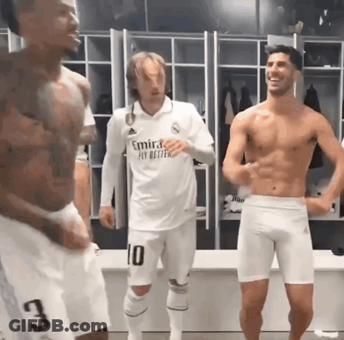 A Shirtless Man In A White Emirates Fly Better Shirt Stands In A Locker Room GIF