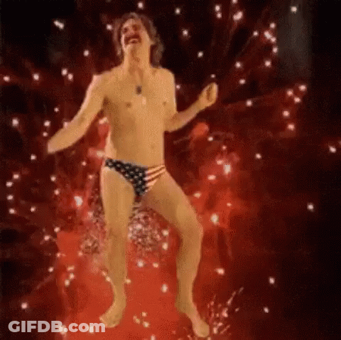 A Shirtless Man In An American Flag Underwear Is Dancing In Front Of A Fireworks Display . GIF