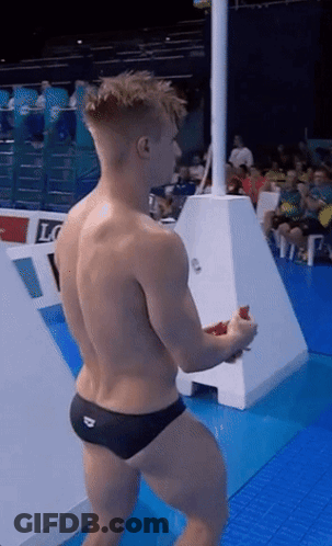 A Shirtless Man In Black Swim Trunks Stands On A Diving Board GIF