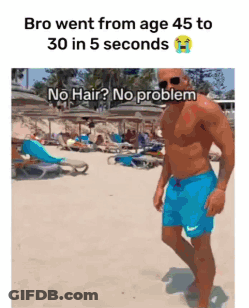 A Shirtless Man In Blue Shorts Is Walking On The Beach GIF