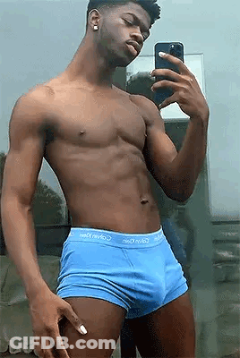 A Shirtless Man In Blue Underwear Is Taking A Selfie With His Cell Phone In Front Of A Mirror . GIF
