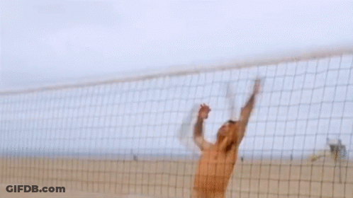 A Shirtless Man In Camouflage Shorts Stands On A Beach GIF