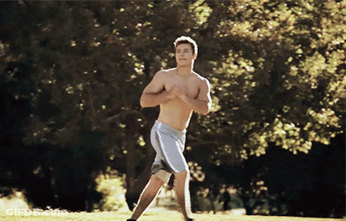A Shirtless Man In Grey Shorts Is Running In A Field GIF