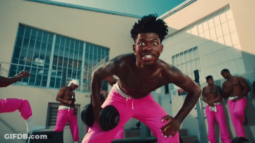 A Shirtless Man In Pink Sweats Is Lifting A Dumbbell GIF