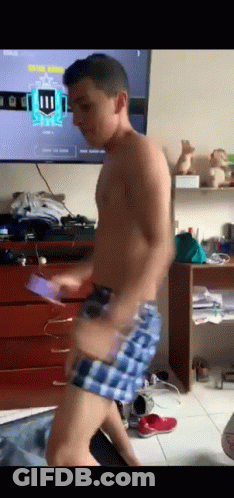 A Shirtless Man In Plaid Shorts Is Dancing In Front Of A Television With The Number 11 On It GIF
