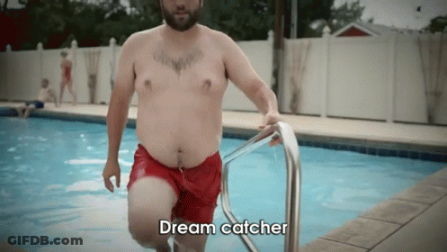 A Shirtless Man In Red Shorts Is Getting Out Of A Swimming Pool With The Words Dream Catcher Above Him GIF