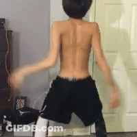 A Shirtless Man In Shorts Is Dancing In Front Of A Door GIF