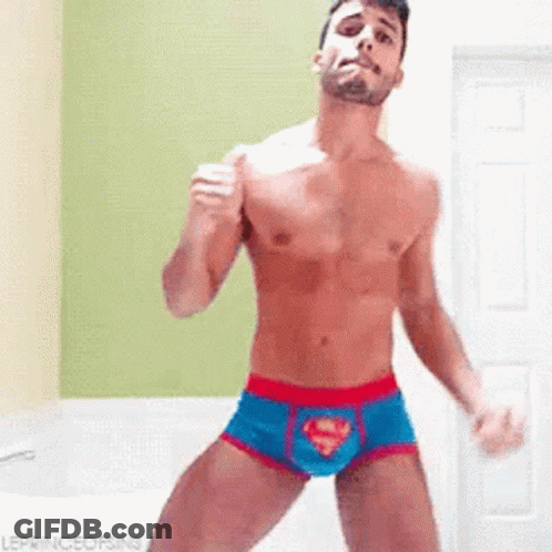 A Shirtless Man In Superman Underwear Is Dancing In A Room . GIF