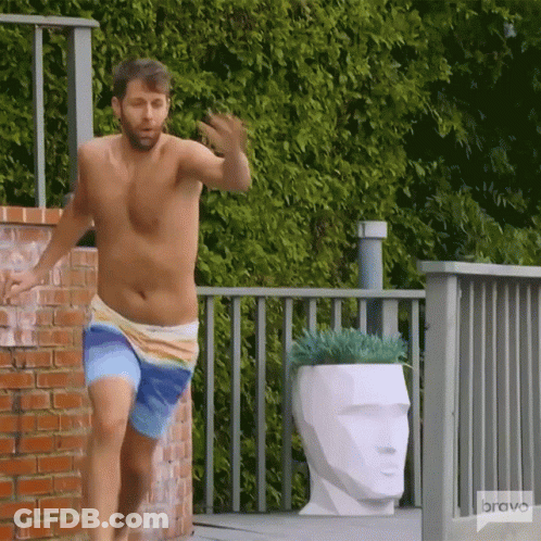 A Shirtless Man In Swim Trunks Is Running On A Deck With A Bravo Logo In The Background GIF